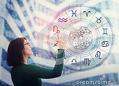 Woman choosing a zodiac sign from the astrological wheel to find the future predictions. Having trust in horoscope, consulting Stock Photo