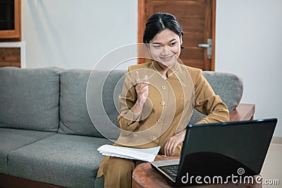 woman in civilian uniform use laptop and paperwork while sitting with hand gestures to explain Stock Photo