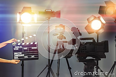 Woman with clapperboard near modern professional video camera in studio Stock Photo