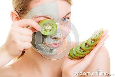 Woman in clay mask on face covering eye with kiwi Stock Photo