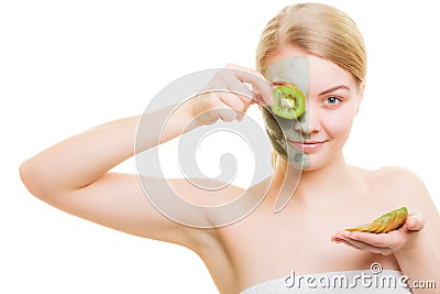 Woman in clay mask on face covering eye with kiwi Stock Photo