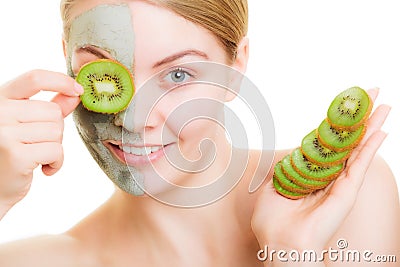 Woman in clay mask on face covering eye with kiwi Stock Photo