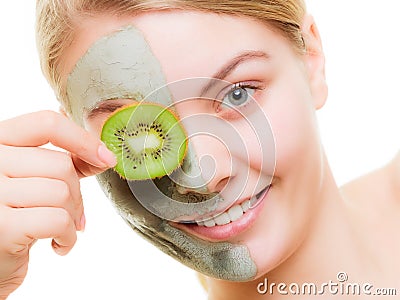 Woman in clay mask on face covering eye with kiwi Stock Photo