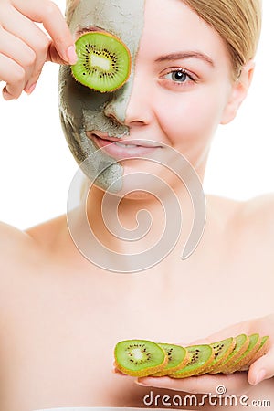 Woman in clay mask on face covering eye with kiwi Stock Photo