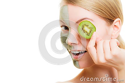 Woman in clay mask on face covering eye with kiwi Stock Photo