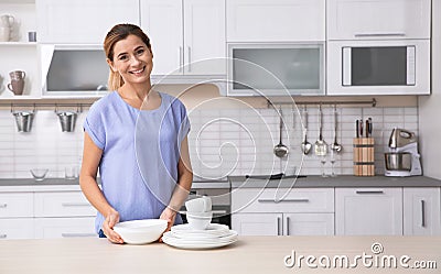 Woman with clean dishes near table in kitchen Stock Photo