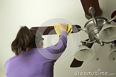 A woman is cleaning ceiling fan Stock Photo