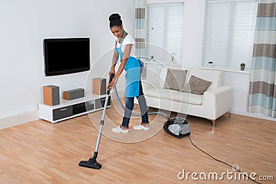 Woman Cleaning Floor With Vacuum Cleaner Stock Photo