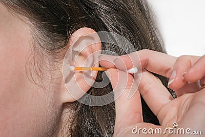 Woman cleaning her ear with plastic stick Stock Photo