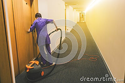 Woman is cleaning the hotel room. Hotel cleaning services. Working as a maid at the hotel. Long hotel corridor with Editorial Stock Photo