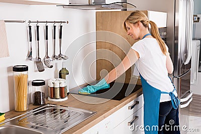 Woman Cleaning Induction Stove In Kitchen Stock Photo