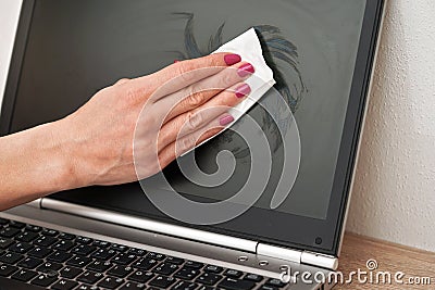 Woman cleaning laptop screen with white tissue, detail on her fingers holding paper towel Stock Photo