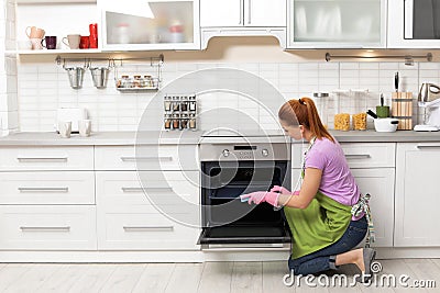 Woman cleaning oven tray with rag Stock Photo
