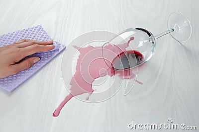 Woman cleaning spilled wine on white wooden table, closeup Stock Photo