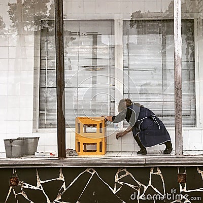 A woman cleans an empty store front on the streets of Tbilisi - GEORGIA - Capital City Beauty Editorial Stock Photo