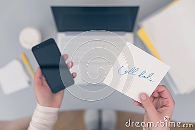 Woman clerk is sitting at office table holding note sticker with message call dad. Stock Photo