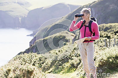 Woman on cliffside path using binoculars Stock Photo