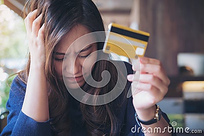 Woman close her eyes while holding credit card with feeling stressed and broke Stock Photo