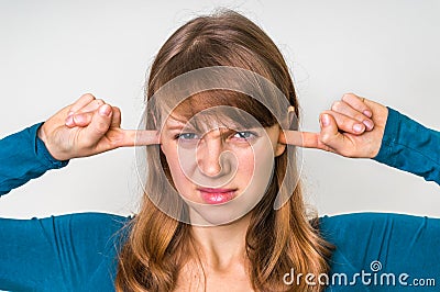 Woman closes ears with fingers to protect from loud noise Stock Photo