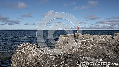 Woman on the coast of the island of Oland on limestone cliffs in Sweden with sun and blue sky Stock Photo