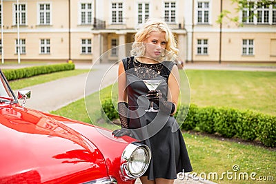 Woman with cocktail glass standing next to retro car Stock Photo