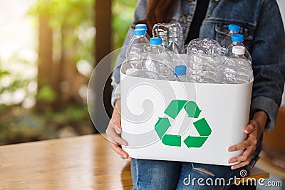 A woman collecting and holding a recyclable garbage plastic bottles into a trash bin Stock Photo