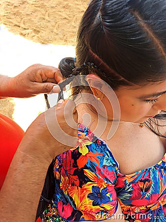 Woman combs her hair on the beach, pays to have braids made, a traditional tourist hairstyle in Acapulco Mexico Stock Photo