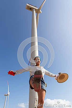 Renewable Energy Elegance: Woman Posing under a Towering Wind Turbine Stock Photo