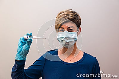 Woman confined at home by the government in prevention of the covid-19 coronavirus looking by measuring her body temperature with Stock Photo