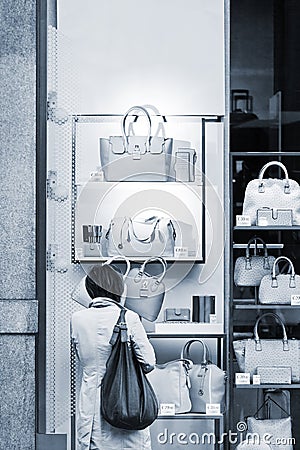 Woman considers bags in a show-window of boutique Editorial Stock Photo