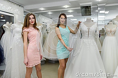 Woman consultant helping bride in choosing bridal gown Stock Photo