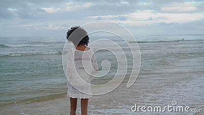 Woman contemplating ocean beach in white outfit. Curly slim girl looking sea Stock Photo