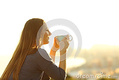 Woman contemplating sunset holding coffee mug Stock Photo