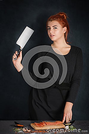 The woman the cook in a black apron with a knife in a hand stand Stock Photo
