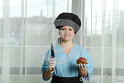The woman the cook holds in one hand a fruit of mango and in other hand a knife Stock Photo