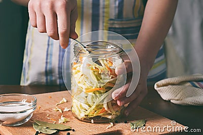 Woman cook sauerkraut or salad on wooden background. Step 5 - Put the cabbage in the jars. Fermented preserved vegetables food Stock Photo