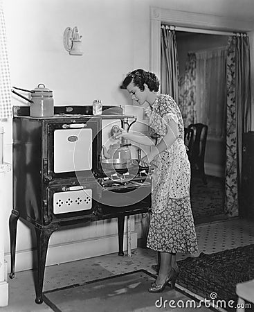 Woman cooking on antique stove Stock Photo