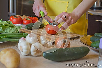 Woman cooking healthy meal in the kitchen. Cooking healthy food at home. Woman in kitchen preparing vegetables. Chef cuts the Stock Photo