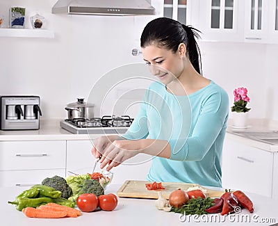 Woman cooking in new kitchen making healthy food with vegetables. Stock Photo