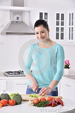 Woman cooking in new kitchen making healthy food with vegetables. Stock Photo