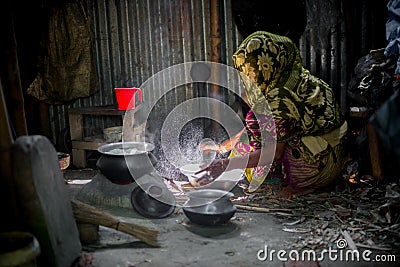 A woman is cooking rice balls on a traditional charcoal-burning clay stove at Narsingdi Editorial Stock Photo