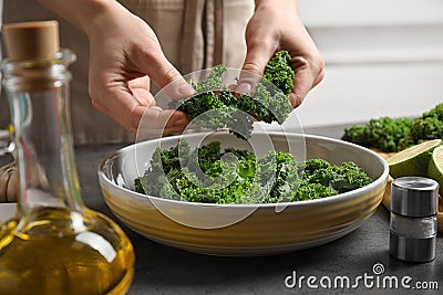 Woman cooking tasty kale salad on grey table Stock Photo