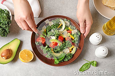 Woman cooking tasty kale salad on light grey table Stock Photo