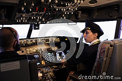 Woman copilot in uniform flying airplane with cockpit command Stock Photo