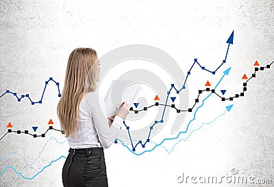 Woman with copybook looking at graphs drawn on wall Stock Photo