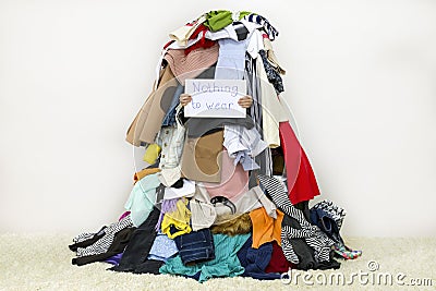 Woman covered with pile of different cloth holding Nothing to wear table sign Stock Photo