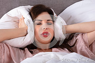 Woman Covering His Ears With Pillow Stock Photo