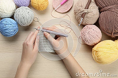 Woman crocheting with grey thread at wooden table, top view Stock Photo