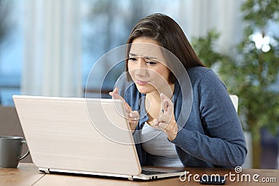 Woman crossing fingers checking on line content Stock Photo