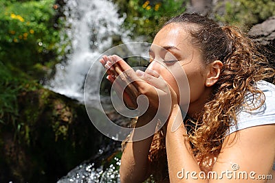 Woman cupping hands drinking water from waterfall Stock Photo